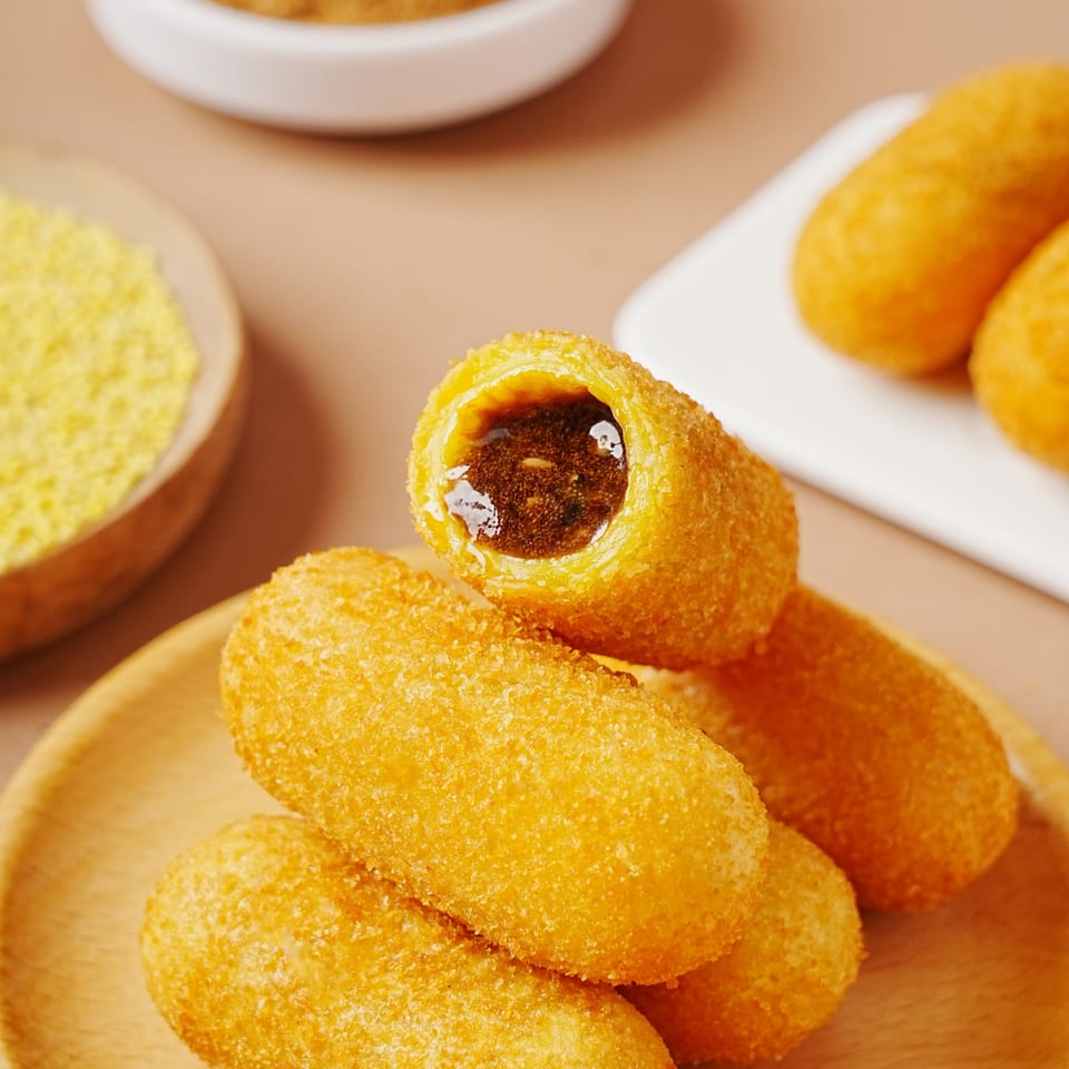 Golden-fried Chinese pastries with a dark, sweet filling, one broken open to show the inside.
